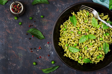 Fusilli pasta with  pesto sauce, green peas and basil. Italian food. Top view. Flat lay.
