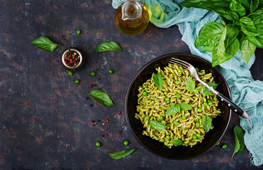 Fusilli pasta with  pesto sauce, green peas and basil. Italian food. Top view. Flat lay.