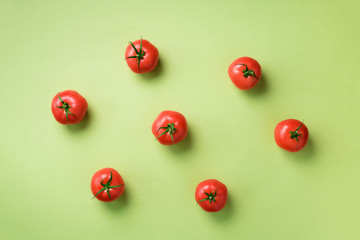Creative pattern of red tomatos on green background. Top view. Copy space. Minimal design. Vegetarian, vegan, organic food and alkaline meal concept