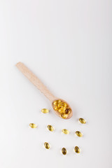 Oil capsule for hair with vitamin E lie on wooden spoon