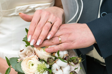 Obraz na płótnie Canvas Wedding rings on the fingers of the bride and groom on the background of the bouquet