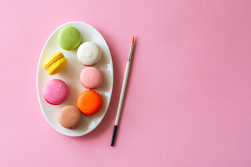 Colorful macarons cookies on a white plate, top view, food background concept.