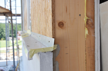 Close up on frame house wall with insulation and drywall.