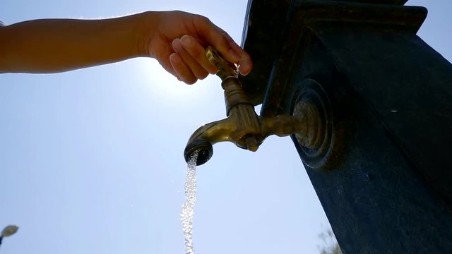 close up shot of a woman's hand, who opens a faucet from which water flows
