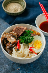 Asian food concept. Udon noodles bowl with eggs, meat, mushrooms, parsley spices and sesame seeds.