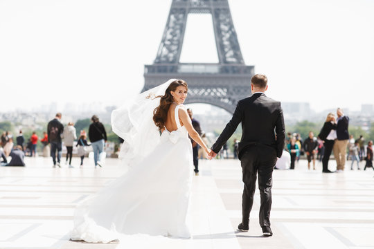 Beautiful wedding couple has fun posing on the square before the Eiffel Tower in Paris