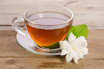 Glass cup of Tea with jasmine flowers on wooden table