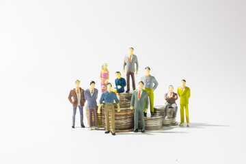 A group of miniature businessman on stack of coins.