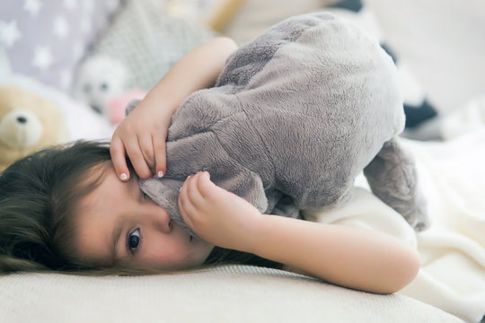 Cute happy little girl sleeping and dreaming in and bed hugging her toy.