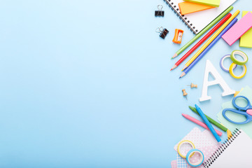 Fototapeta premium Colorful stationary school supplies on blue trending background, space or text flat lay