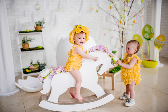 Two little girls in yellow dresses play in the studio with Easter decorations