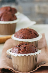 Homemade chocolate zucchini muffins with chocolate chips.  White stone background.
