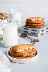 Fresh healthy milk and oatmeal cookies with cereals on grey concrete background