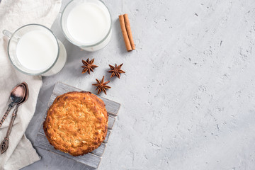 Fresh healthy milk and oatmeal cookies with cereals on grey concrete background. Copy space