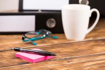 business desk with coffee cup, glasses, folder, paper and pen