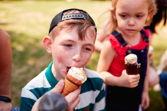The stylish boy eatting ice cream in the park