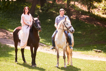 The lovely couple in love riding on horses along park