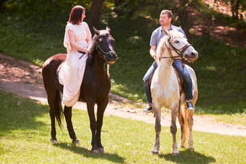 The lovely couple in love riding on horses along park