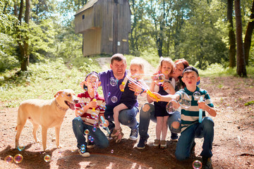 The children blowing bubbles and mother,father and dog sitting near them