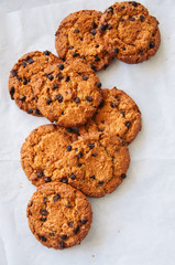 Traditional American homemade chocolate chips cookies on a wire rack on a white stone background.