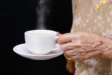 Senior woman holding a coffee cup .