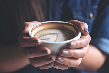 Closeup image of a woman holding a cup of coffee before drinking with feeling good and relaxed  in cafe