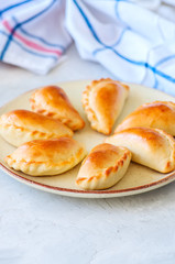 Homemade potato stuffed empanadas served on plate. White stone background.