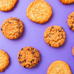 Assorted American traditional old fashioned cookies. Oatmeal and chocolate chips cookies on a purple background. Top view and square image.