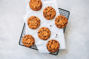 Homemade chocolate chips cookies on a wire rack on a white stone background. Traditional American old fashioned treats. Top view.