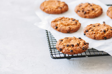 Homemade chocolate chips cookies on a wire rack on a white stone background. Traditional American old fashioned treats. Close up.
