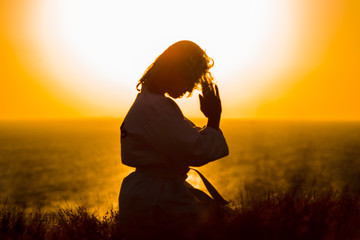 Silhouette of a samurai in a kimono while meditating on the ocean coast, at sunrise. The concept of a healthy lifestyle, unity with nature, meditation.
