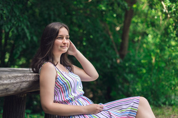 Young girl sitting in bench on summer sunny day.