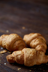 Tasty buttery croissants on an old wooden table, close-up, selective focus, shallow depth of field.