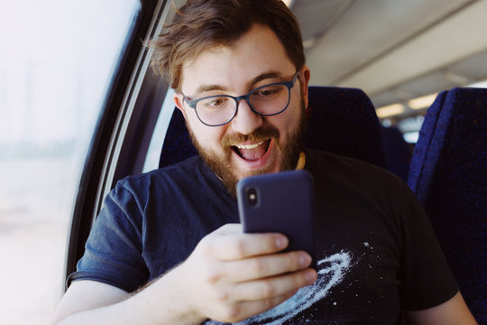 Laughing man in a train holding smartphone
