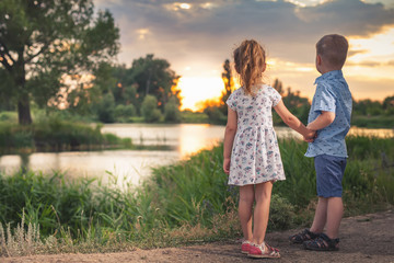 Happy kids walking outdoor at park hold their hands.