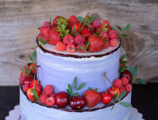 beautiful two-tiered cake with purple cream and berries of strawberries, raspberries and cherries