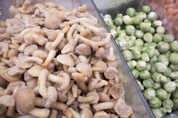 Assortment of frozen vegetables and mushrooms in the supermarket fridge
