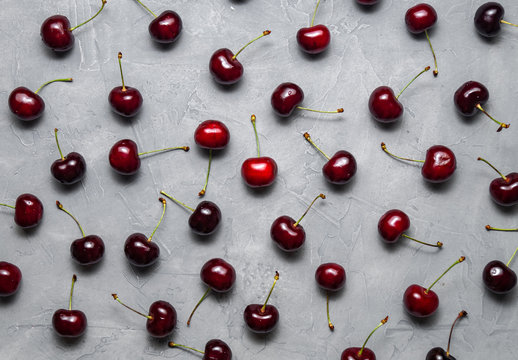 Flat background: Fresh ripe red Cherry is evenly spread out on a gray background.
