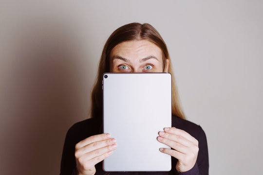 Beautiful surprised blonde woman holding tablet