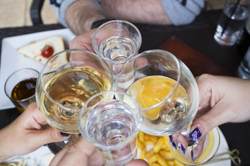 at the table, men's and women's hands toast clink glasses