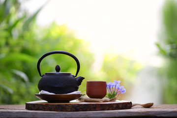 Obraz na płótnie Canvas Old black tea pot with brown cup and flower