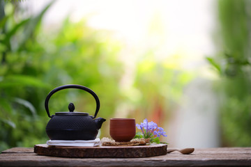 Old black tea pot with brown cup and flower