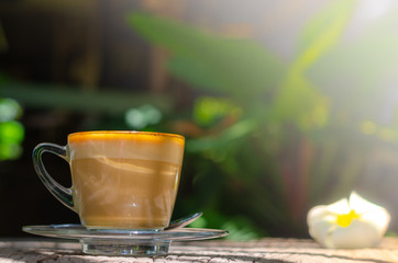 Cup of coffee on wood table in sunset time with soft light in morning time.