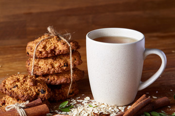 Christmas concept with a cup of hot tea, cookies and decorations on a log over wooden background, selective focus