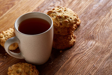 White porcelain mug of tea and sweet cookies on wooden background, top view, selective focus