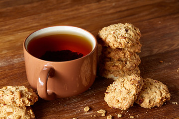Porcelain cup of tea and sweet cookies on wooden background, top view, selective focus