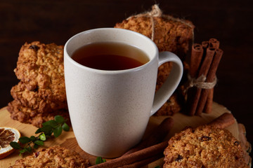 White cup of tea and cookies on a log over country style wooden background, close-up, selective focus