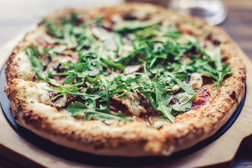 Closeup photo of pizza with fresh basil and rocket salad or arugula 