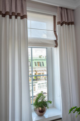 Curtains in the interior. From natural light linen, with decorative braid In the room,