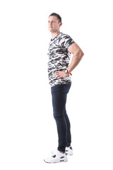 Naklejka premium Profile of confident sport casual man in military shirt with hands on hips looking up. Full body isolated on white background. 